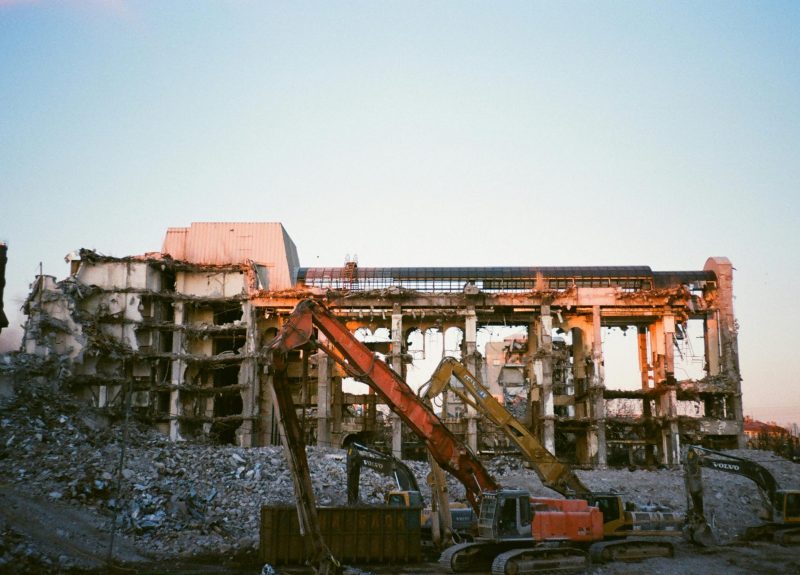 Construction machinery at a building demolition site during sunset.